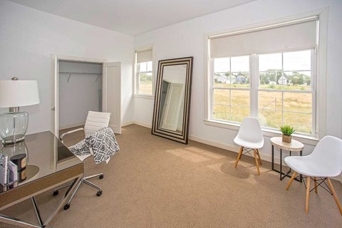A room with a brown carpet and white chairs.