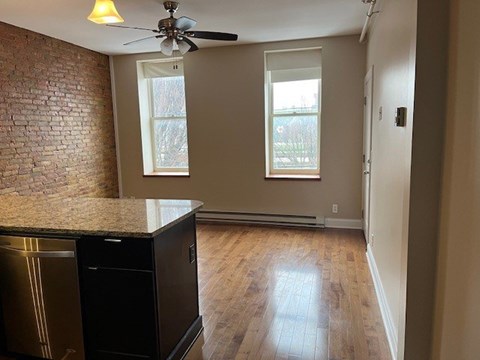 A kitchen with a black fridge and a ceiling fan.