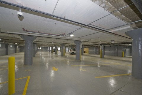 a large parking garage with pillars and a yellow arrow in the floor