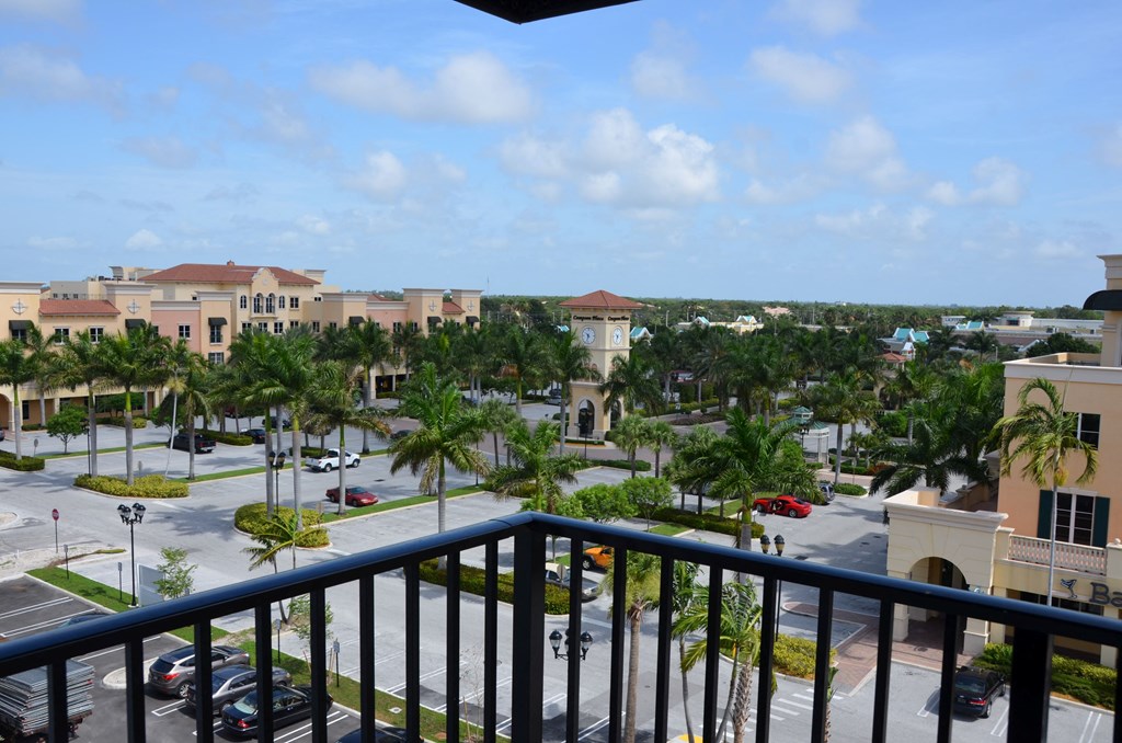 A view from a balcony overlooking a parking lot surrounded by palm trees.