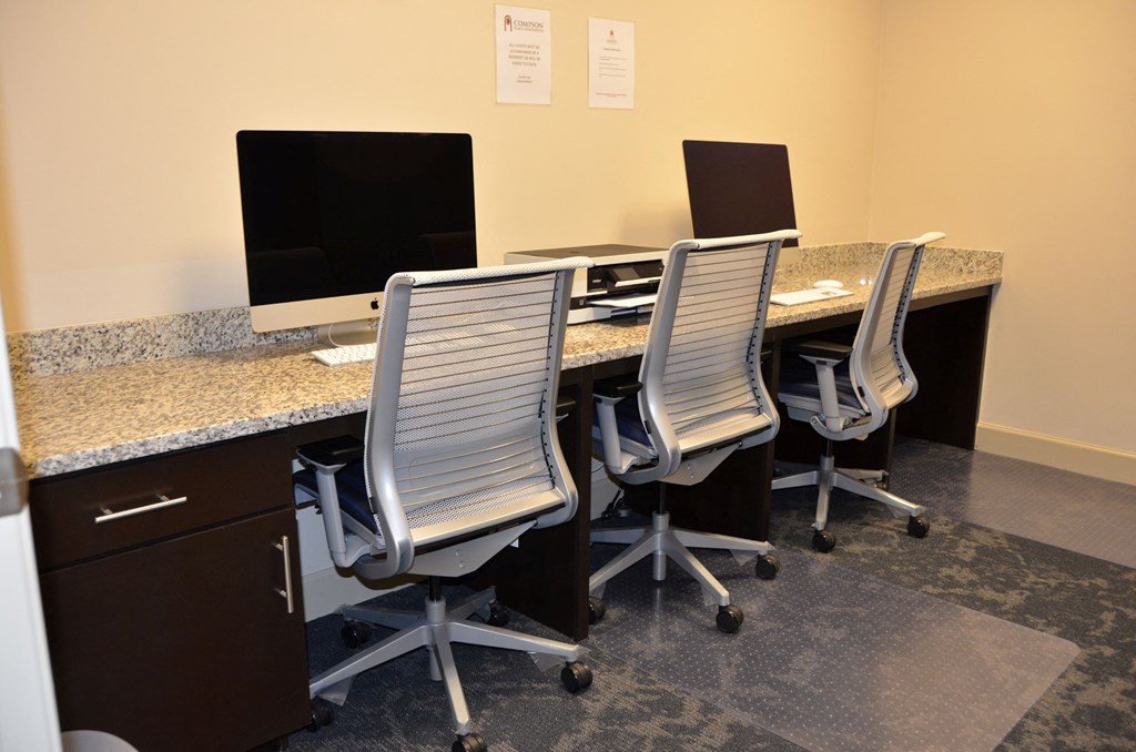 Three chairs are arranged around a desk with two computer monitors and a printer.