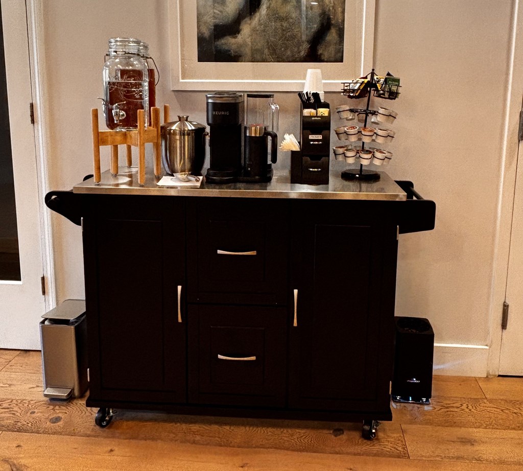 A black coffee cart with a variety of items on top of it.