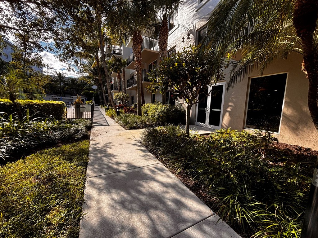 A walkway with an apartment building and trees in the background.