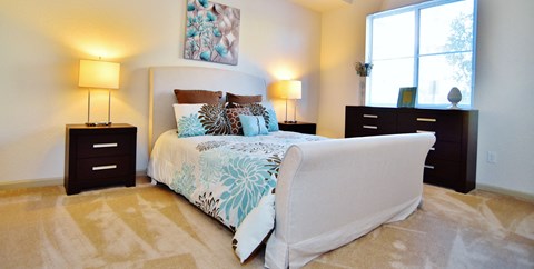 A bedroom with a large bed, two lamps, and a dresser.