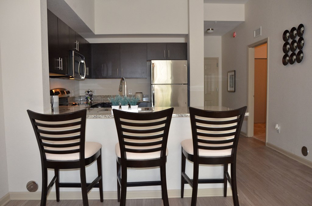 Three wooden chairs are placed in front of a kitchen island.