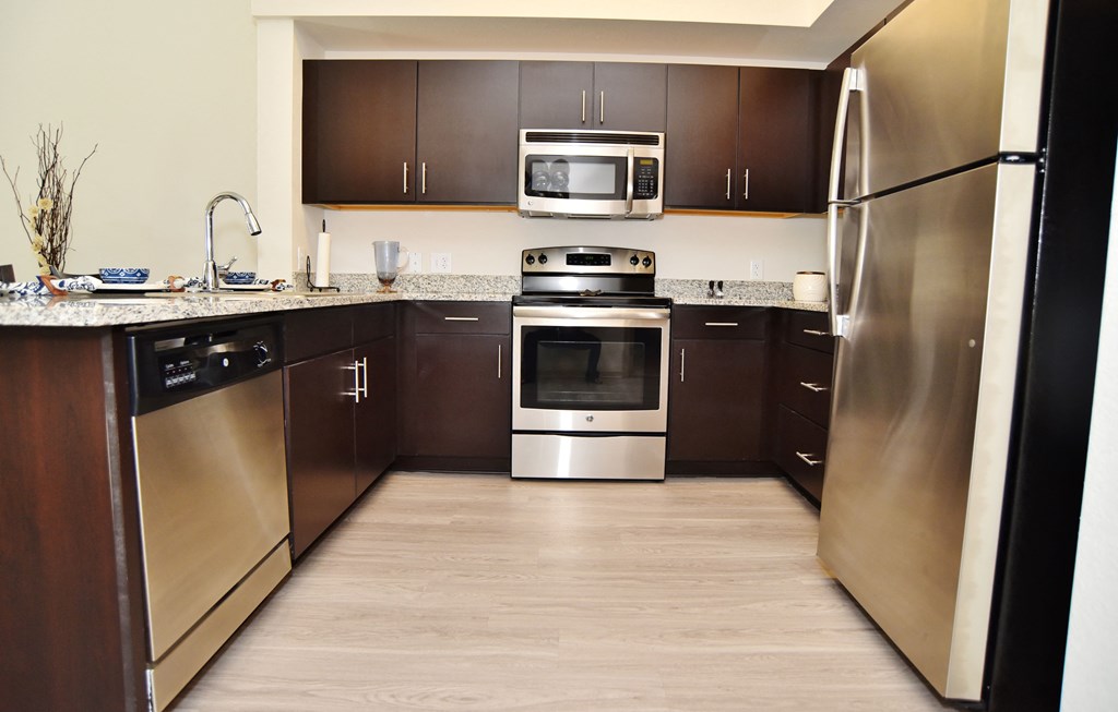 A modern kitchen with dark wood cabinets and stainless steel appliances.