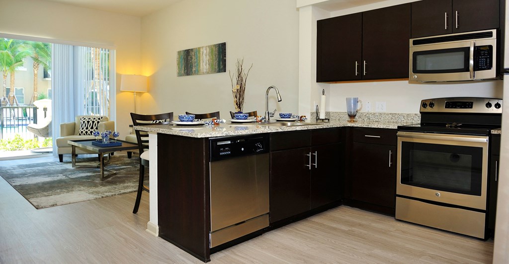 A modern kitchen with dark brown cabinets and stainless steel appliances.
