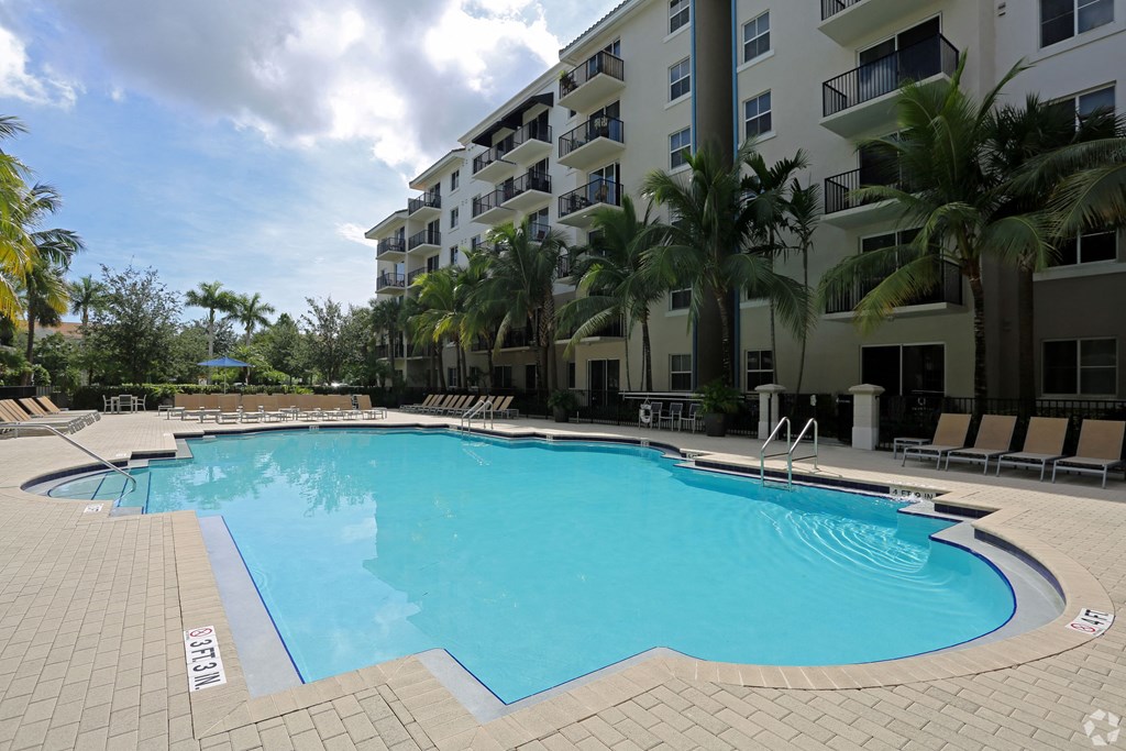 A swimming pool surrounded by palm trees and apartment buildings.