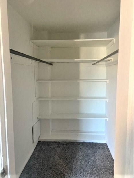 a walk in closet with white shelves and a door