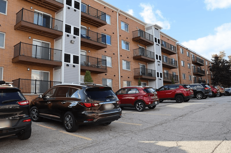 a parking lot full of cars in front of an apartment building