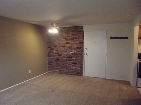an empty living room with a brick wall and a white door