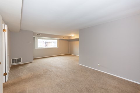 an empty living room with white walls and a window