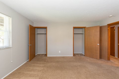 a bedroom with three closets and a carpeted floor