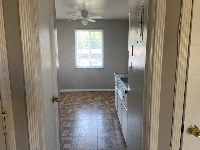 a small kitchen with a ceiling fan and a window