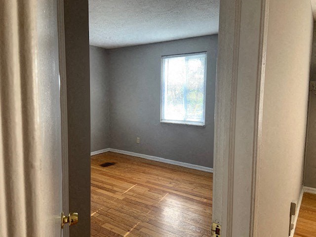 an empty room with a window and wooden floors