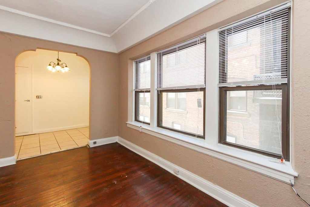 a living room with three windows and a hard wood floor
