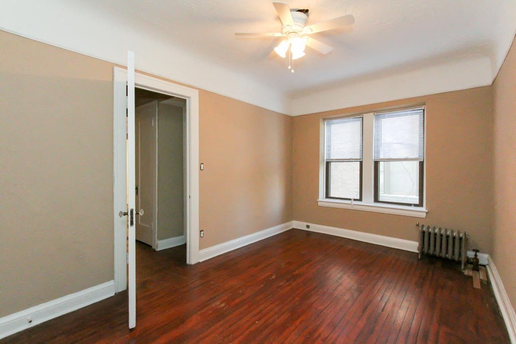 an empty living room with wood floors and a ceiling fan
