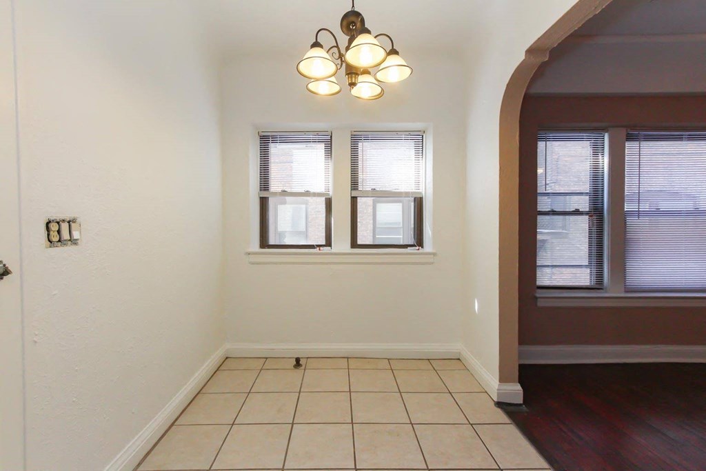 a dining room with a tiled floor and two windows