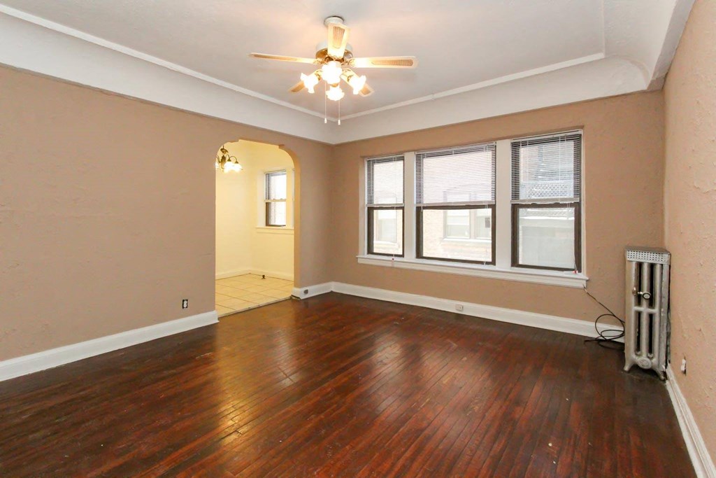 an empty living room with wood floors and a ceiling fan
