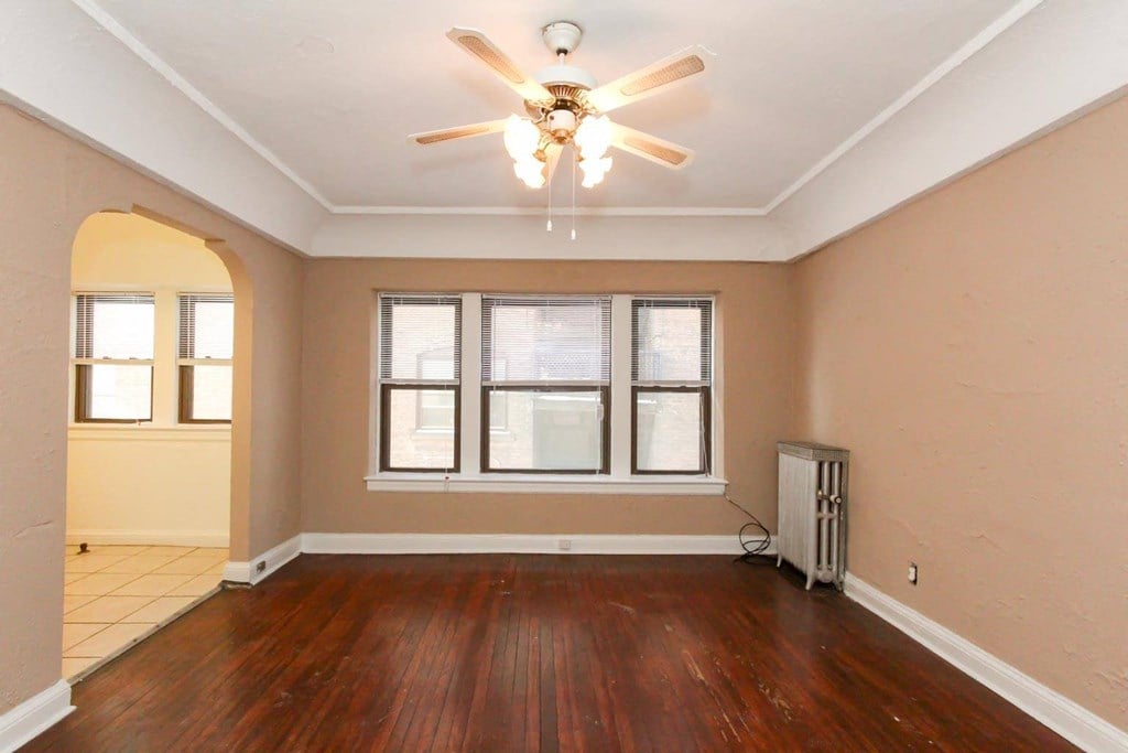 an empty living room with wood floors and a ceiling fan