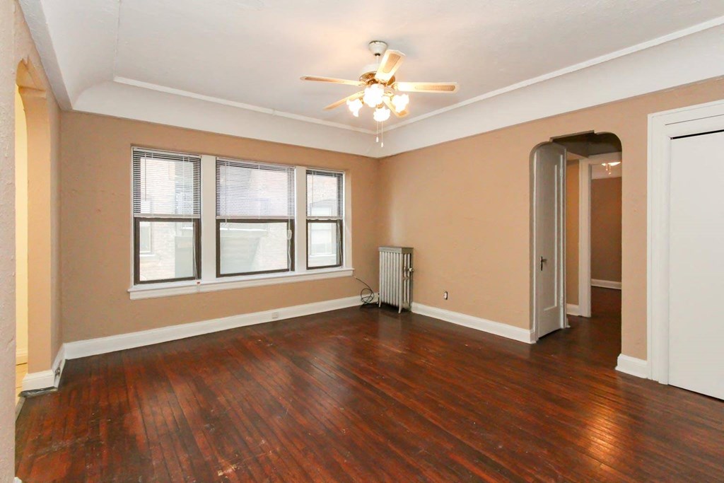 an empty living room with wood floors and a ceiling fan