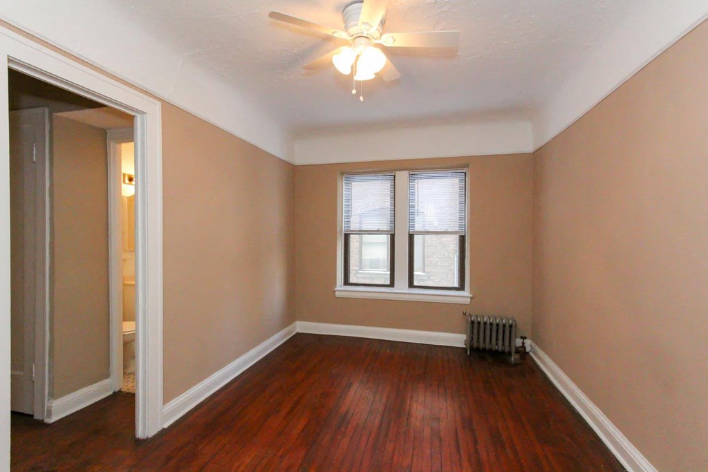 an empty living room with wood floors and a ceiling fan