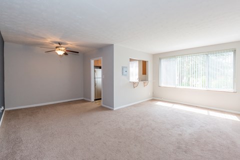an empty living room with a ceiling fan and a window