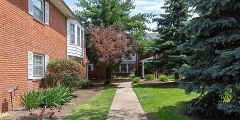 a sidewalk in front of a brick apartment building