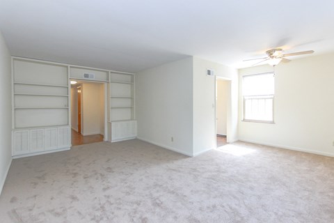 an empty living room with white walls and a ceiling fan