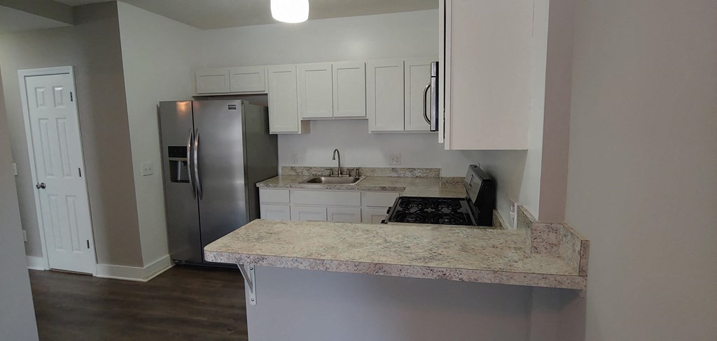 an empty kitchen with white cabinets and a stainless steel refrigerator