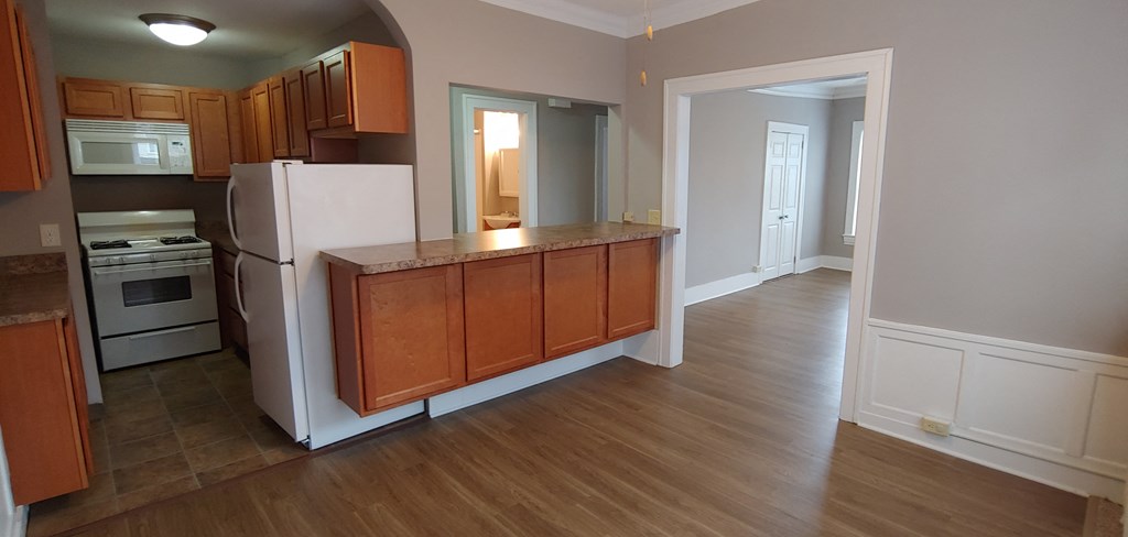 an empty kitchen with wooden floors and a white refrigerator