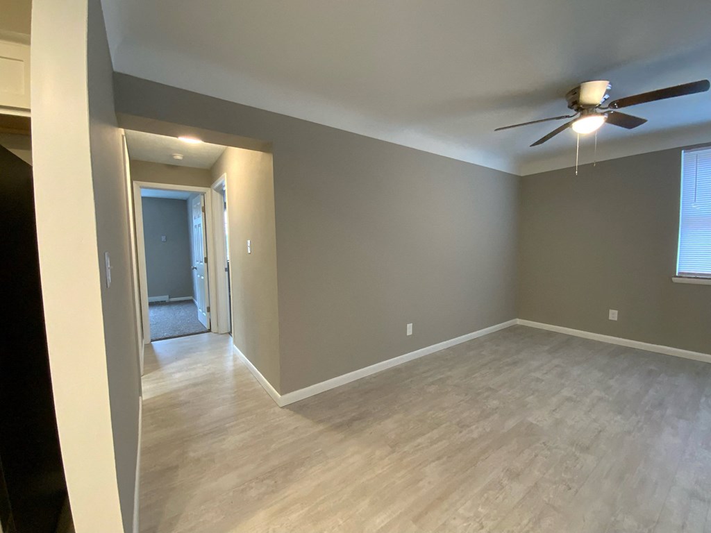 an empty living room with wood floors and a ceiling fan