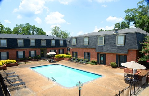 A swimming pool surrounded by a fence and chairs.