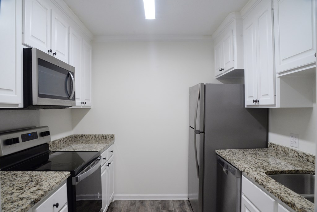 A kitchen with granite countertops and white cabinets.