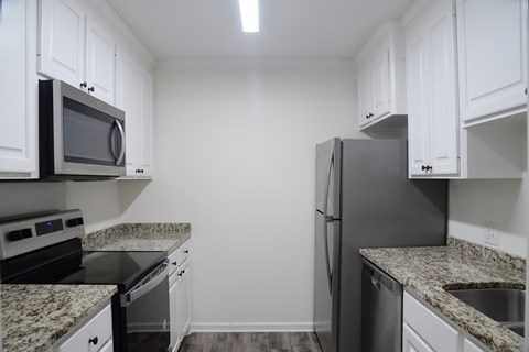 A kitchen with granite countertops and white cabinets.
