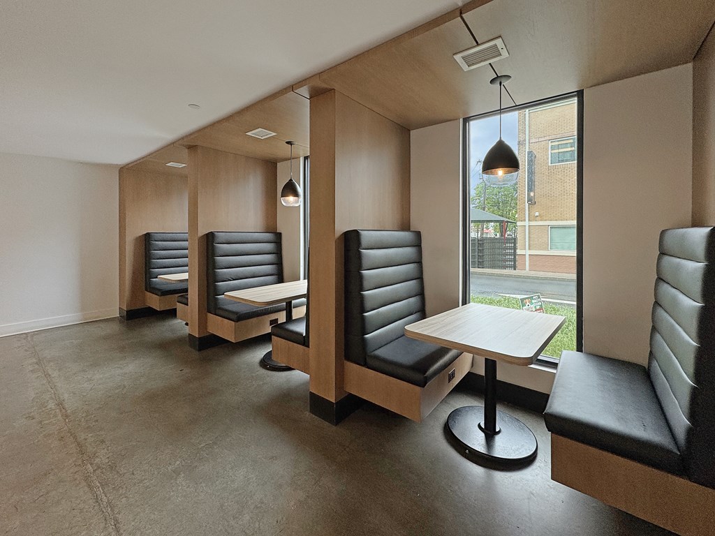A row of black leather chairs are lined up in a room with a table and a window.