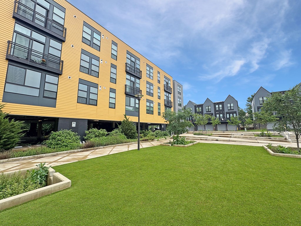A modern building with a yellow and black exterior and a green lawn in front.