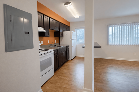 A kitchen with a white stove top oven and black cabinets.