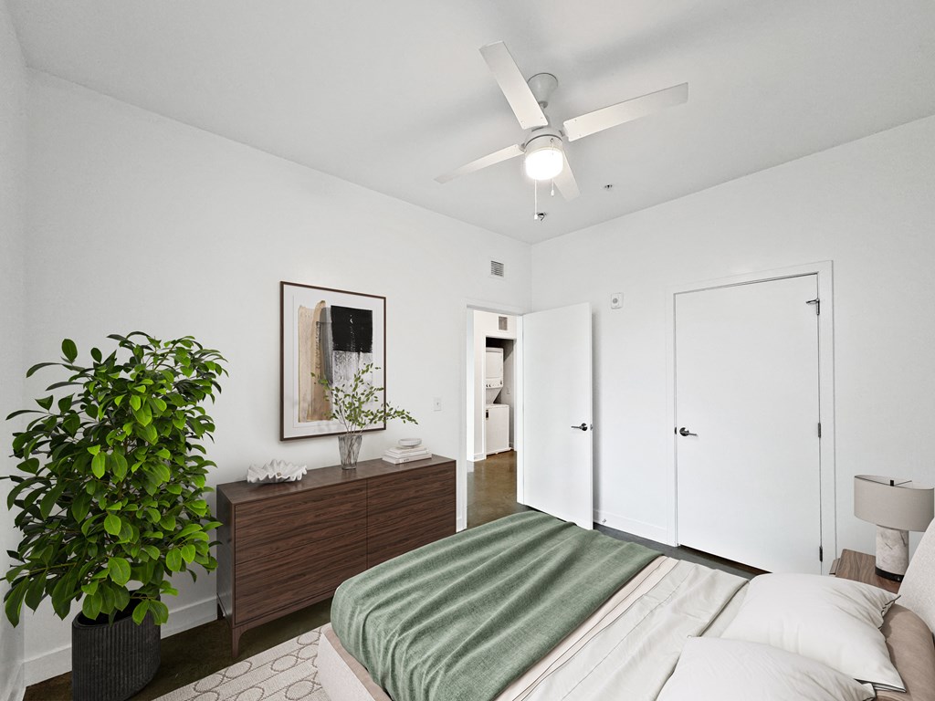 A bedroom with a bed, dresser, and a ceiling fan.