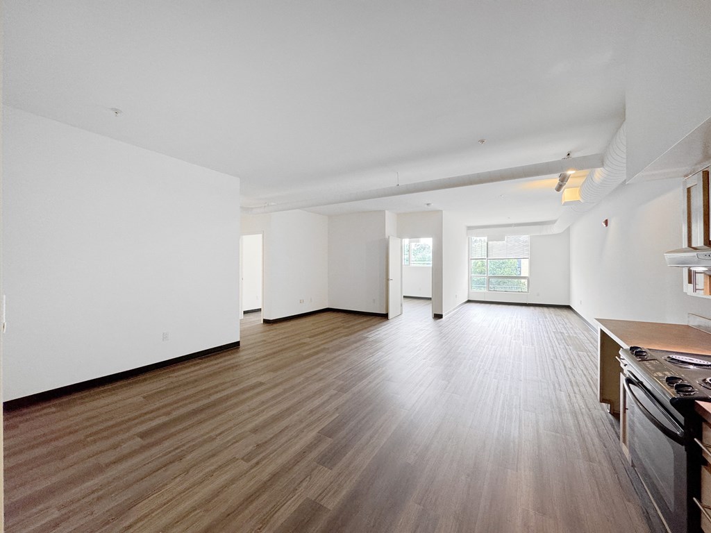 A large empty room with wooden flooring and white walls.