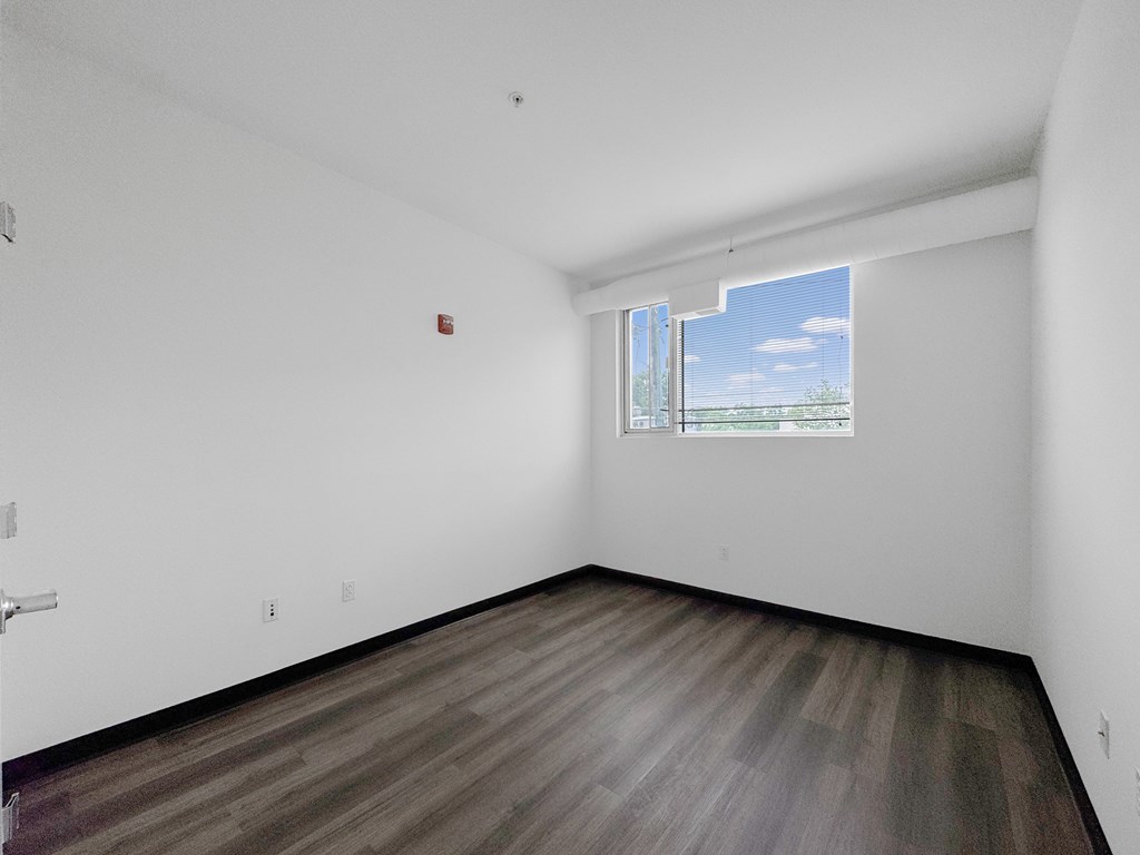A room with a window and a wooden floor.