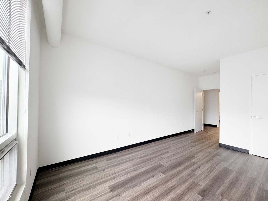 A room with wooden flooring and white walls.