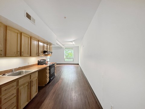 A long, narrow kitchen with wooden cabinets and a dark countertop.