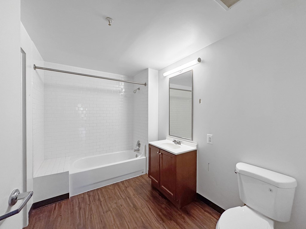 A white bathroom with a wooden cabinet and a white toilet.