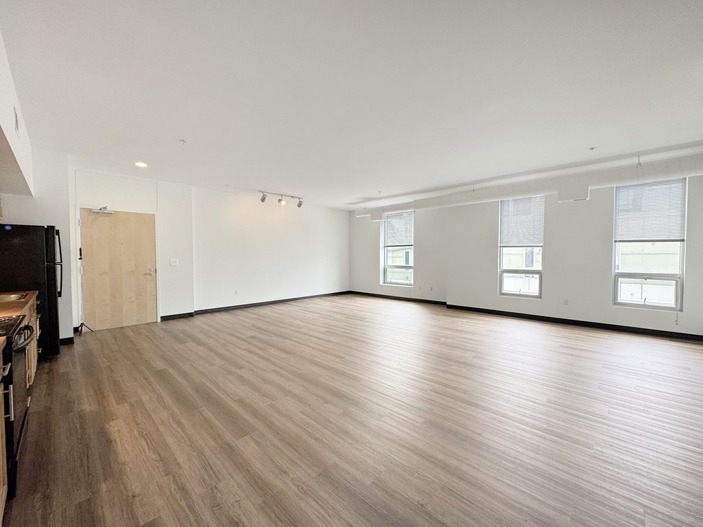 A large empty room with wooden flooring and white walls.