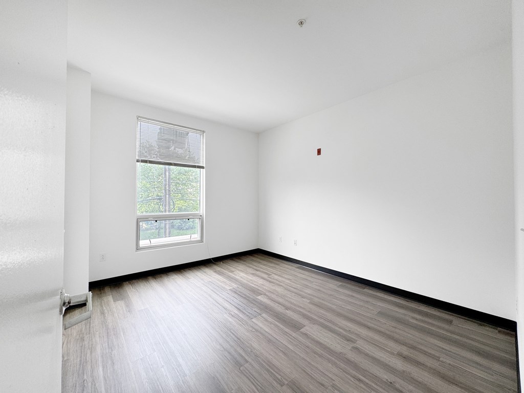 A room with a window and wooden flooring.