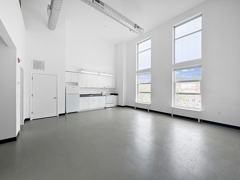 A large empty room with white walls and grey floor.