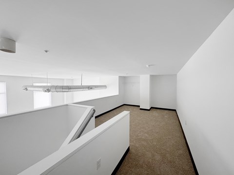 A white room with a carpeted floor and a skylight.