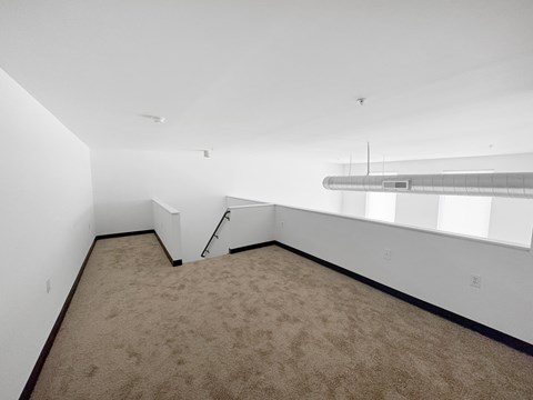 Empty room with carpeted floor and white walls.