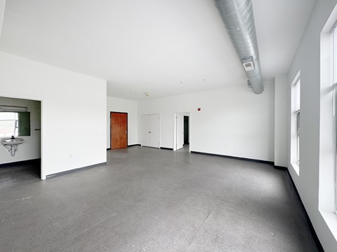 A large empty room with a grey floor and white walls.